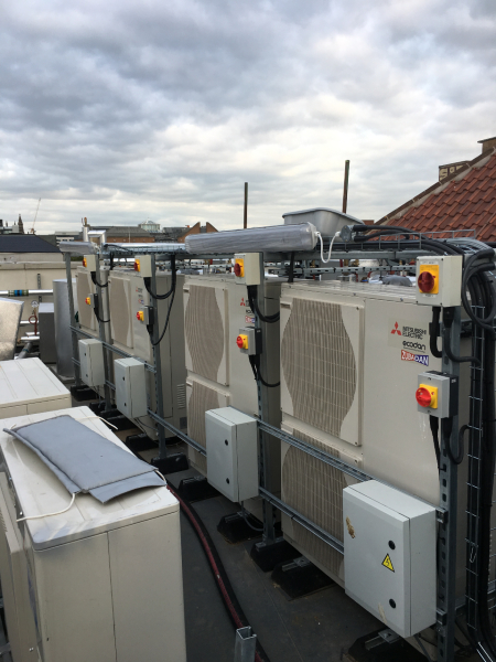 A bank of air source heat pumps on the roof of a building