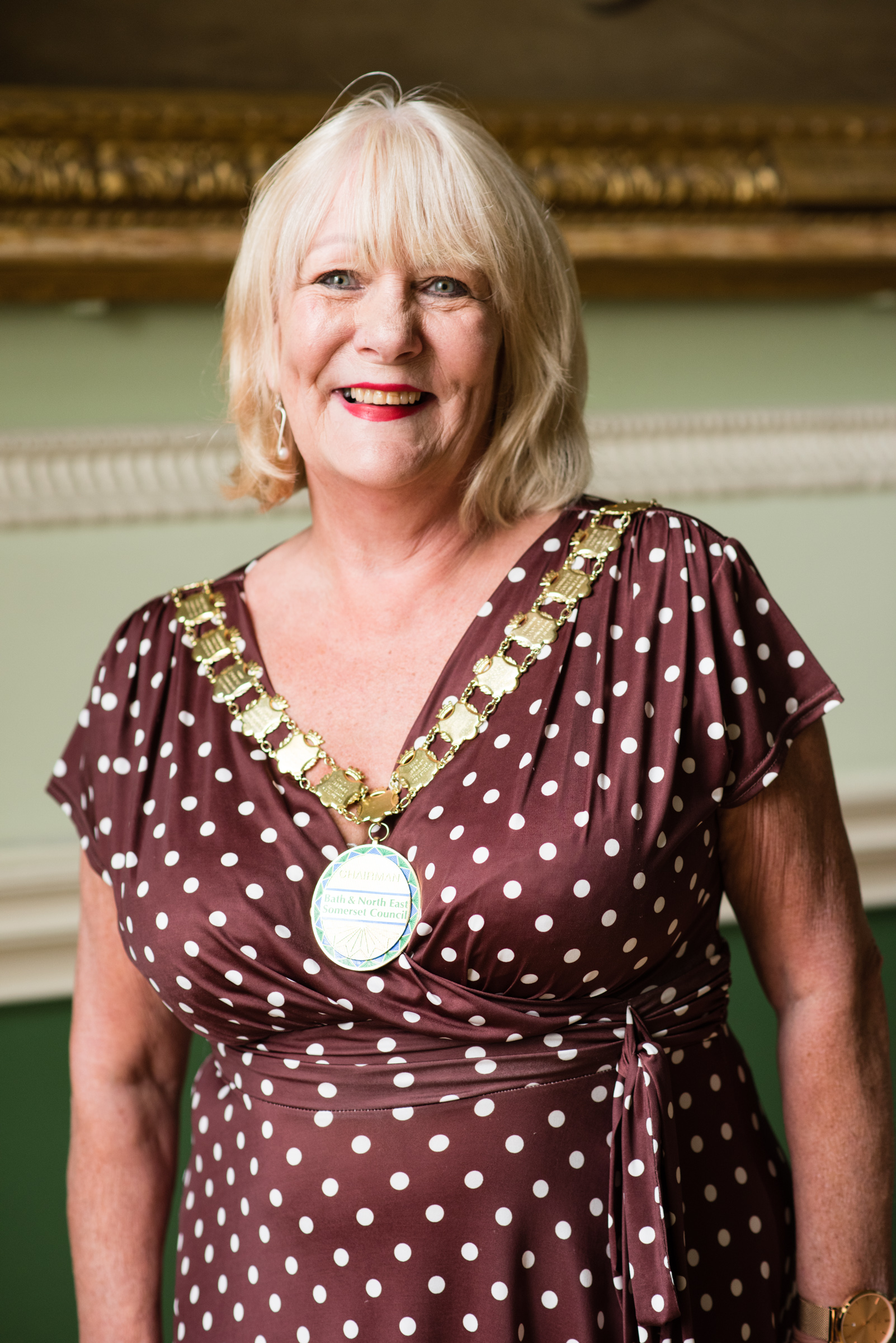 A portrait image of Councillor Karen Walker, a blonde lady in a dark brown, polka dot dress